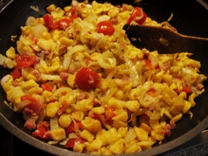 Chicoréestreifen, Zwiebelwürfel und Tomatenstücke werden einige Minuten mit den Knöpfle gebraten.