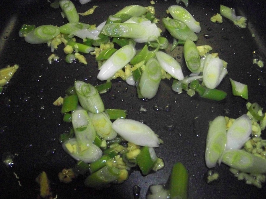 Das Gemüse aus der Pfanne nehmen das restliche Erdnussöl darin erhitzen und die Lauchzwiebeln und den Ingwer darin glasig dünsten.