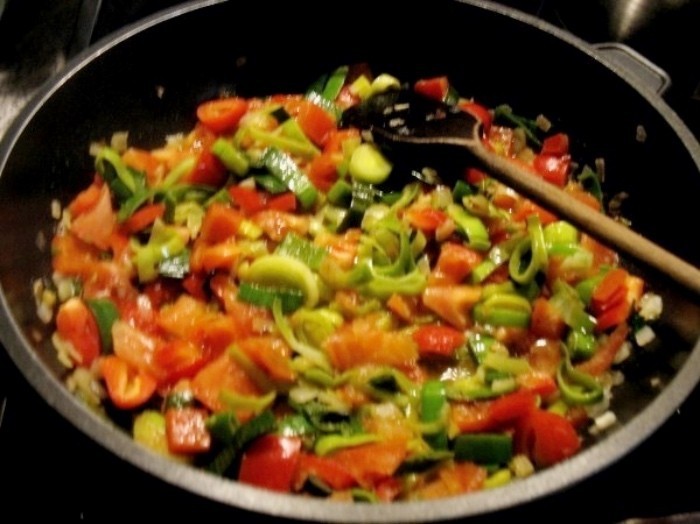 Zwiebelwürfel, Lauch, Paprika- und Tomatenstückchen werden in einer großen Pfanne bei mittlerer Hitze angebraten.