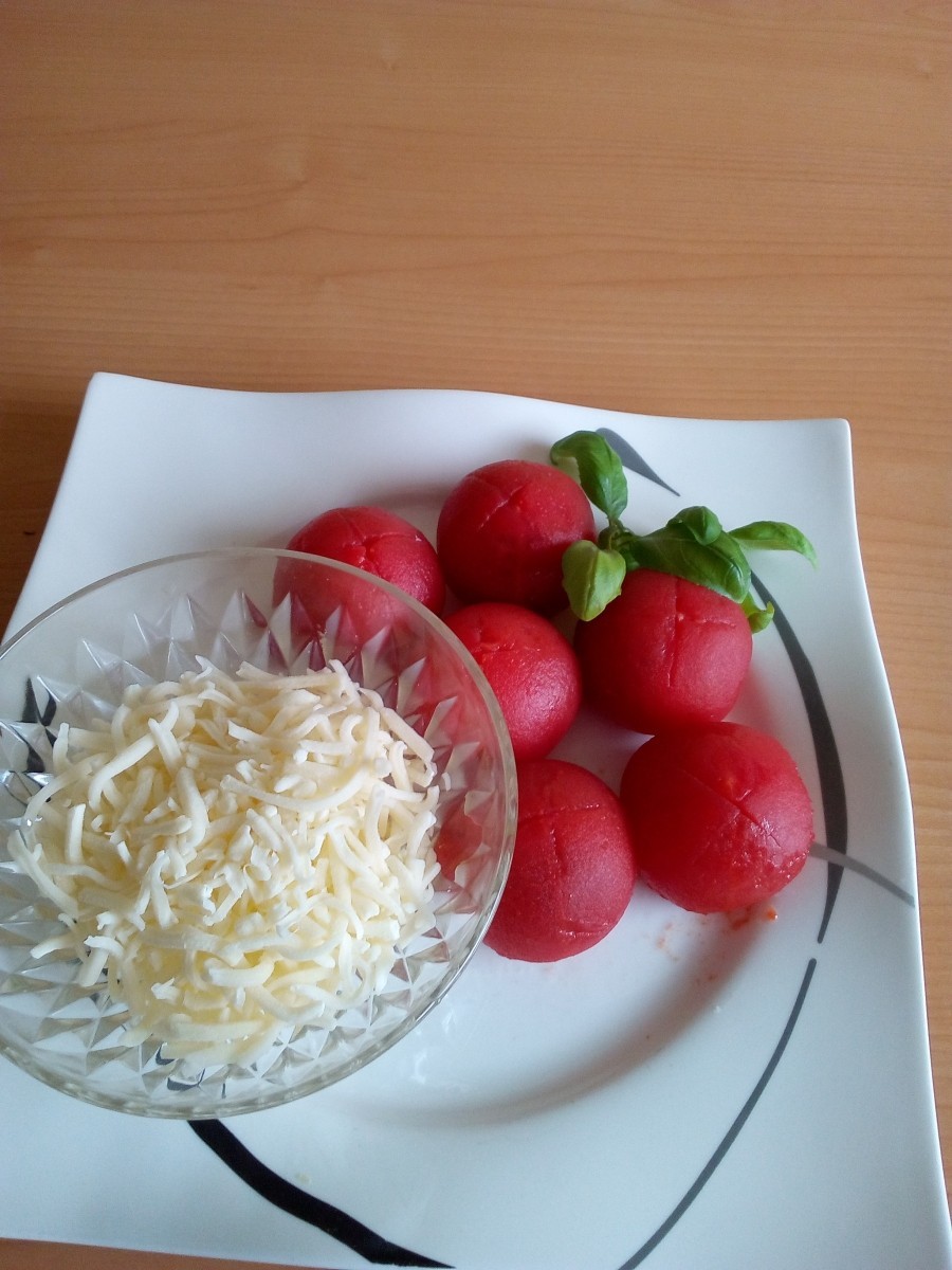 Die Tomaten sodann etwas tiefer kreuzweise einschneiden, leicht mit Salz oder Kräutersalz bestreuen und den Gratinkäse darüber geben. 