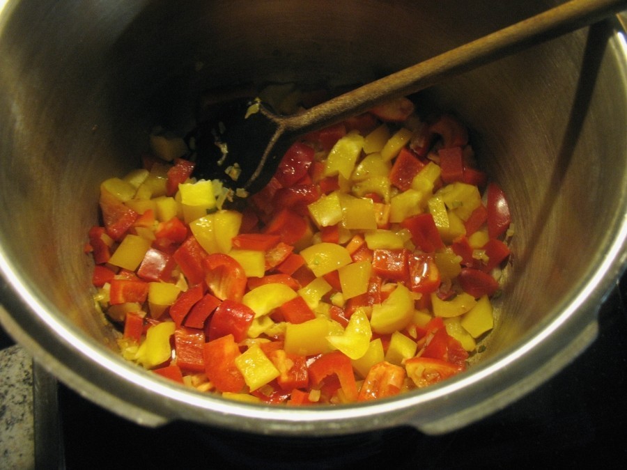 Zwiebelwürfel, klein geschnittene Knoblauchzehen und Paprikaschoten werden im erhitzten Butterschmalz angebraten, dann kommen Ketchup und Tomatenmark dazu.
