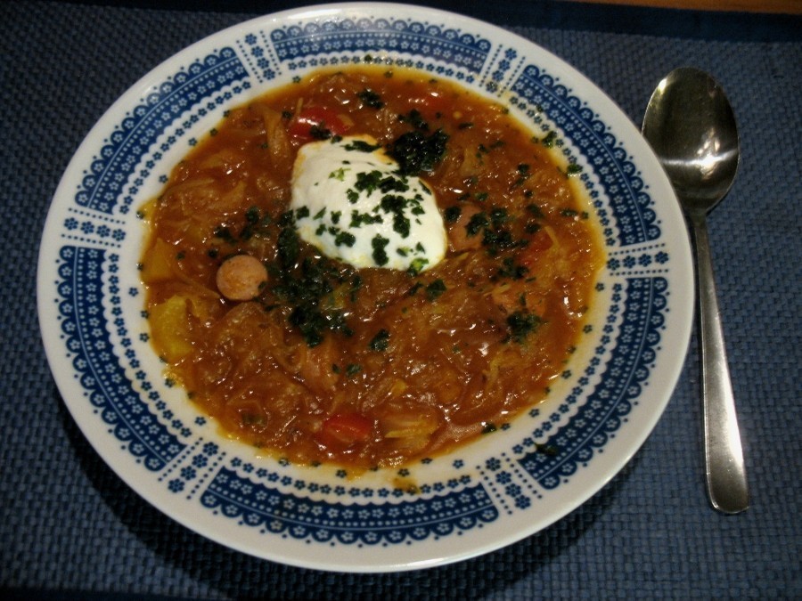 Die Sauerkraut-Paprika-Suppe wird mit einem Klecks saurer Sahne und mit Petersilie bestreut serviert.