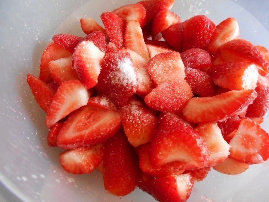 Die Erdbeeren werden geputzt, gewaschen und geviertelt, dann werden sie mit Zucker bestreut und vorsichtig umgerührt.