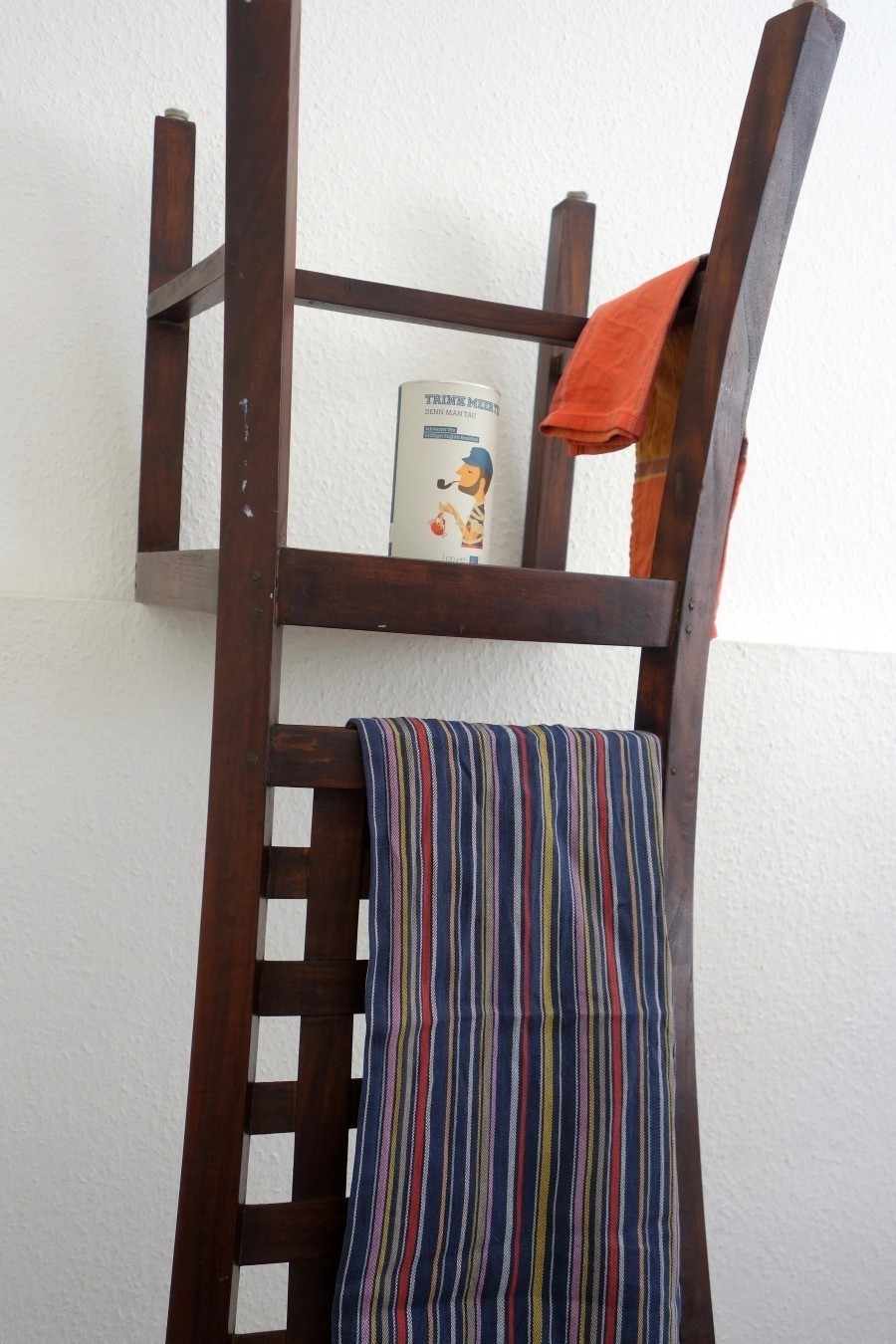 Um den Stuhl als Regal und Handtuchhalter zu verwenden, wird er einfach auf den Kopf gestellt und mit Dübeln und langen Schrauben an der Wand fest verschraubt.