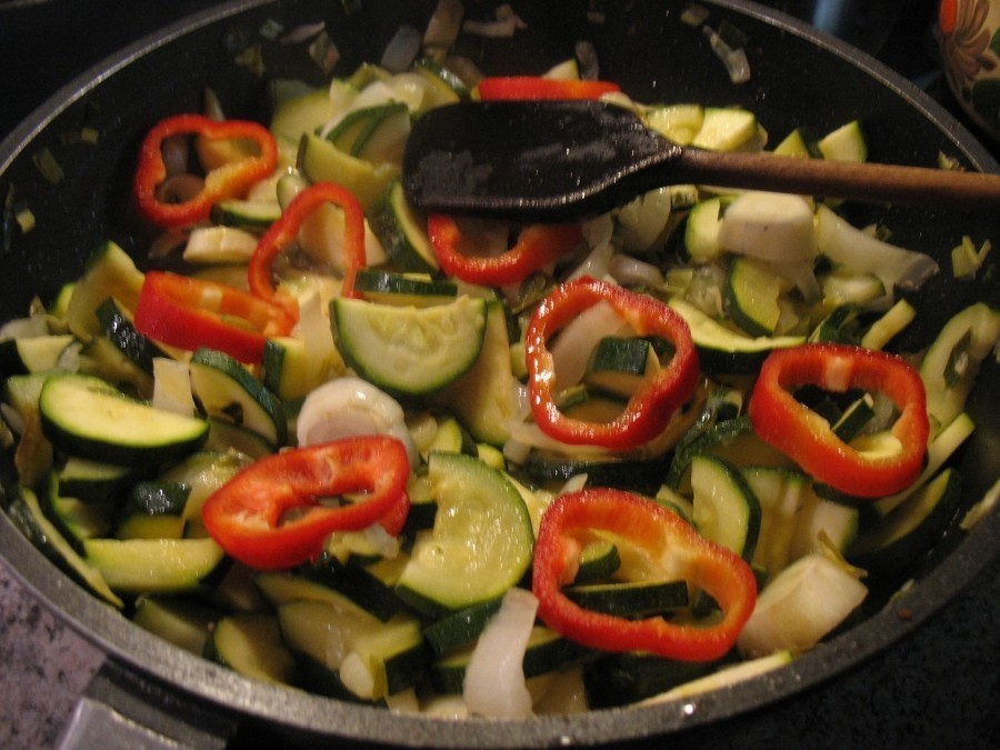 Die halbierten Zucchinischeiben und Paprikaringe dazugeben und etwa 10 Minuten bei mittlerer Hitze unter mehrfachem Wenden anbraten.