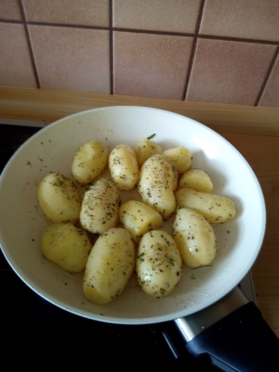 In einer Pfanne ebenfalls etwas Butter erhitzen und die abgeschälten Kartoffeln hineingeben, den gehackten Rosmarin drüber streuen sowie pfeffern und salzen.