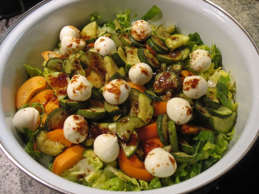 Die Mozzarella-Mini-Kugeln werden über den Salat verteilt, zum Schluss träufelt man die Vinaigrette darüber.
