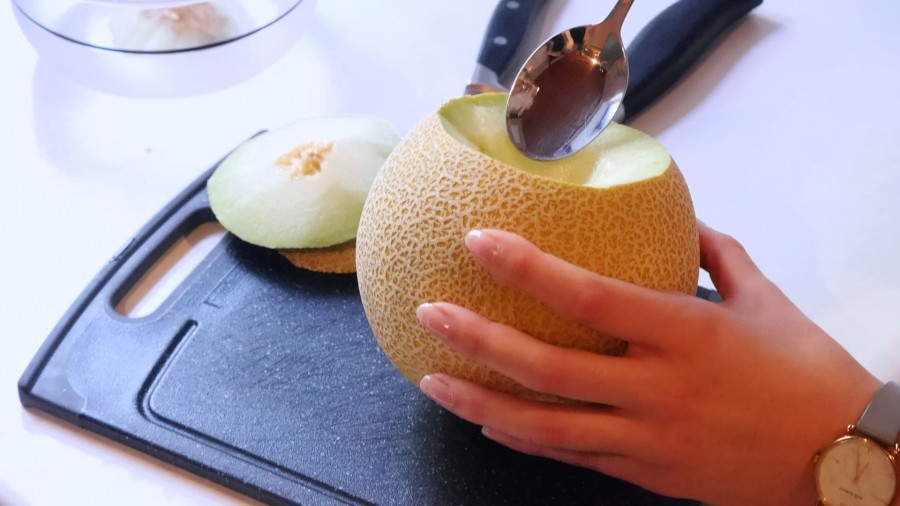 Mit einem Löffel zuerst das Kerngehäuse aus der Melone holen. Dann mundgerechte Stücke vom Fruchtfleisch abkratzen.