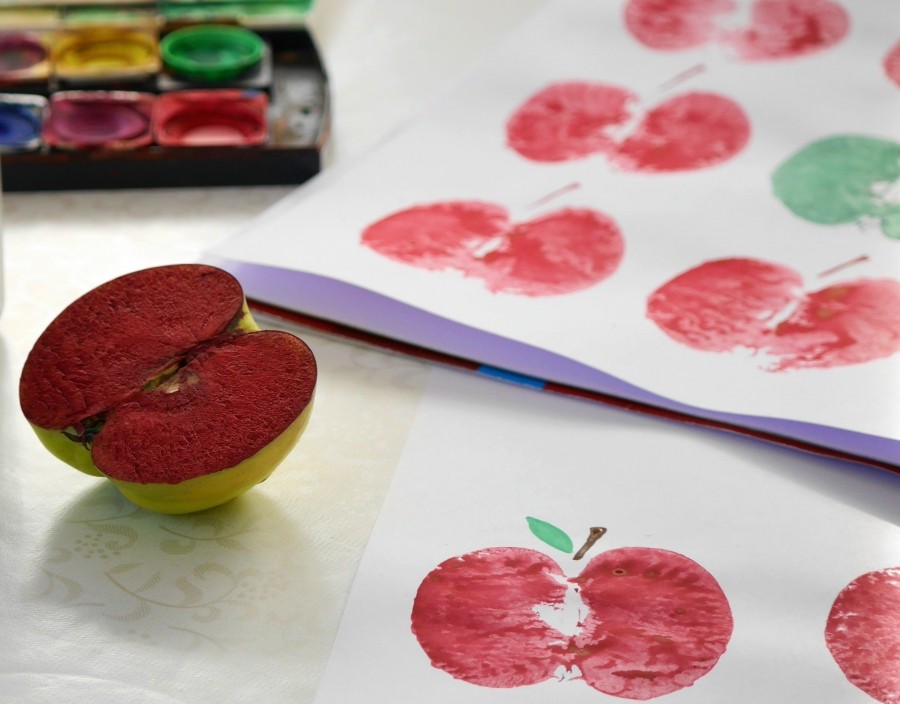 Den Apfel mit einem großen Messer halbieren, darauf achten, dass er mit einem Schnitt gerade durchgeschnitten wird. Die Farbe auftragen und auf das Papier drücken.