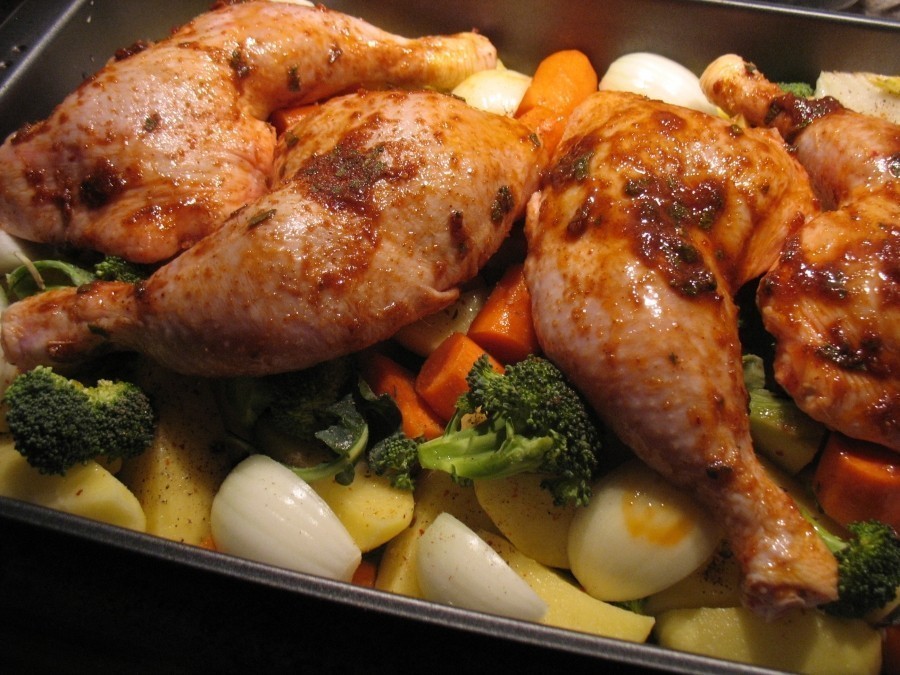 Die marinierten Hähnchenschenkel aus dem Kühlschrank legt man auf das Gemüsebett und schiebt die Pfanne in die vorgeheizte Backröhre.
