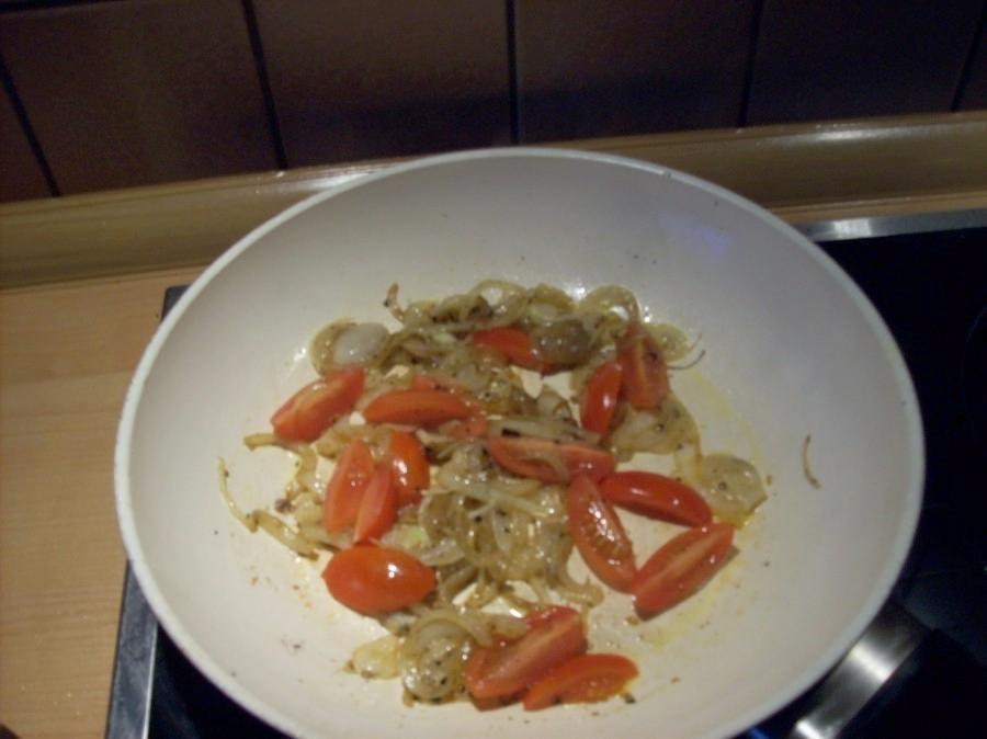 In der gleichen Pfanne wird nun noch die in dünne Scheiben geschnittene Zwiebel hellbraun angebraten und die geachtelten Tomaten kommen ebenfalls dazu, werden mit Pfeffer und Salz gewürzt.