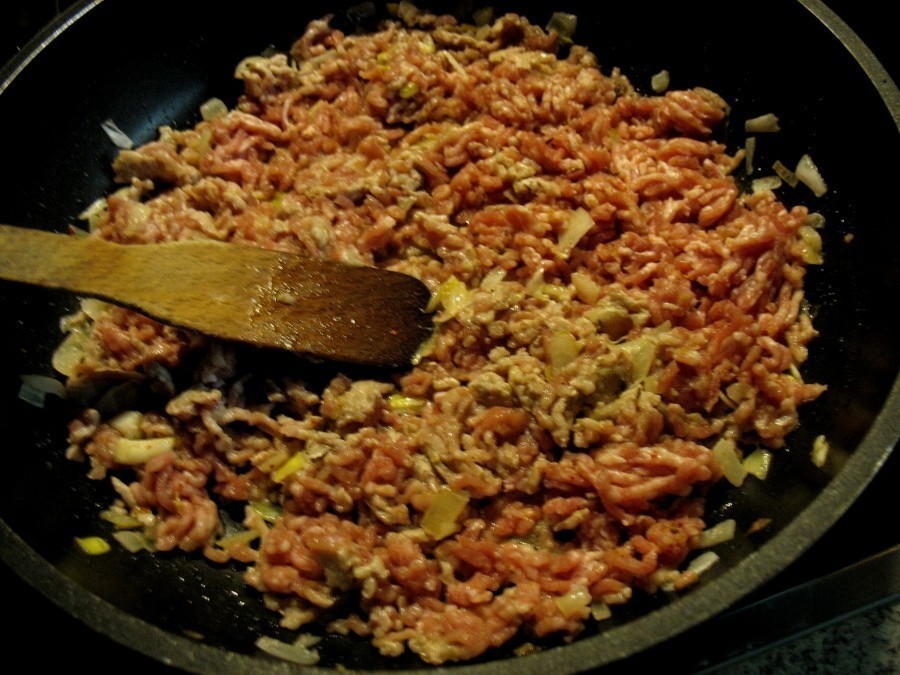 Auf der beschichteten Pfanne werden Zwiebeln und Knoblauch im heißen Öl glasig angedünstet, dann kommt das Hackfleisch dazu und wird krümelig angebraten.