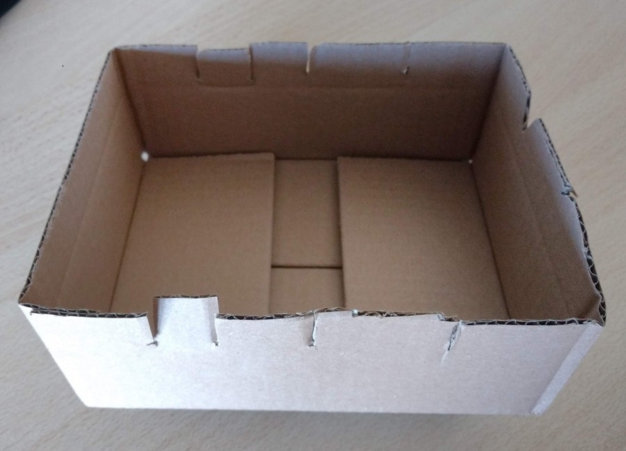 Den Karton an den beiden Schmalseiten mit einer Schere / Cutter ca. 1cm tief einschneiden oder ein kleines Dreick aus dem Karton herausschneiden. 