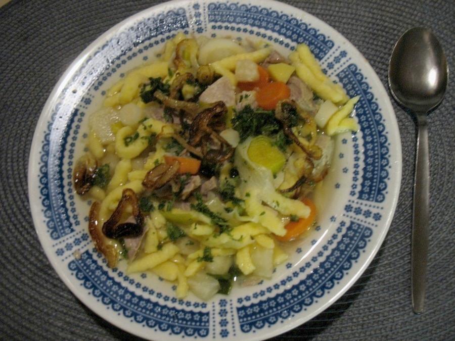Der Gemüsetopf wird mit den angebratenen Zwiebelscheiben und den gehackten Kräutern serviert.