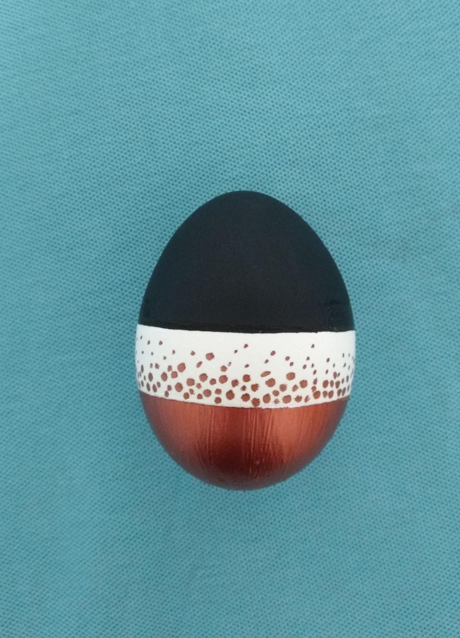 Ein fertig gestaltetes Ei in den Farben kupfer, schwarz und weiß mit einem raffinierten Punktmuster.