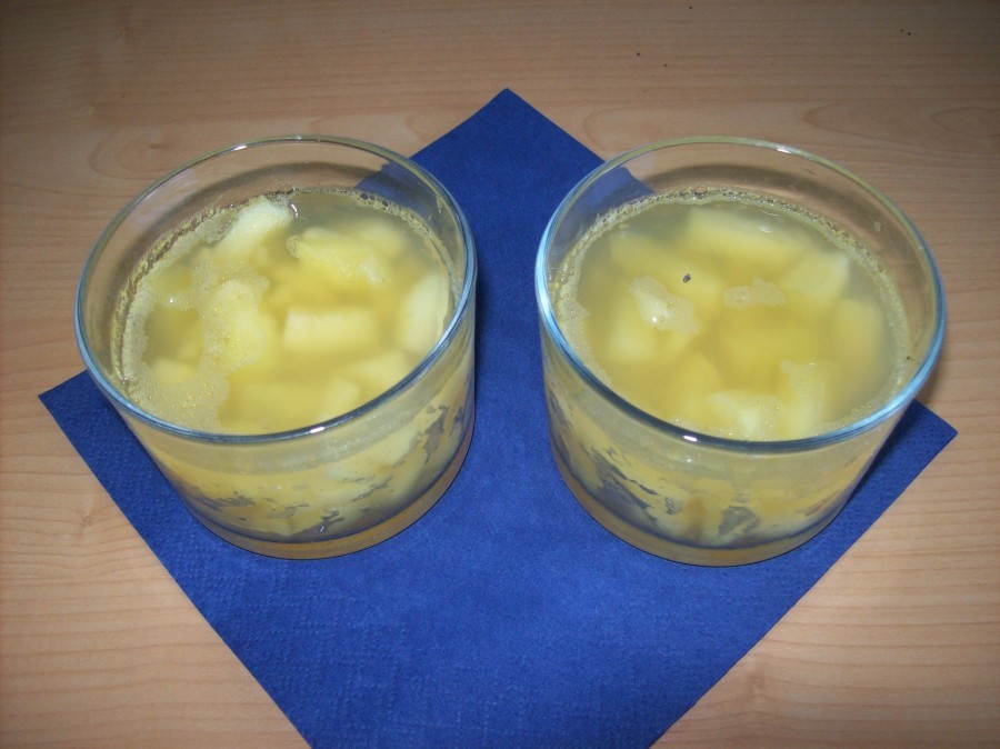 Der zurückgebliebene Saft wird auf die Apfelstückchen gegossen. Nach Wunsch kann nun noch für die Erwachsenen jeweils ein TL des gewünschten Alkohols über das Apfelwürfel-Gelee verteilt werden.