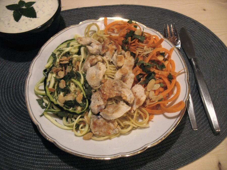 Bunter Spaghetti-Teller mit sahniger Kräuter-Senf-Soße. Zutaten sind unter anderem Geschnetzeltes sowie Karotten- und Zucchinispaghetti.