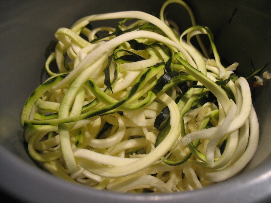 Die Zucchini-Spaghetti aus dem Spiralschneider werden mit etwas weißem Pfeffer und Salz gewürzt.