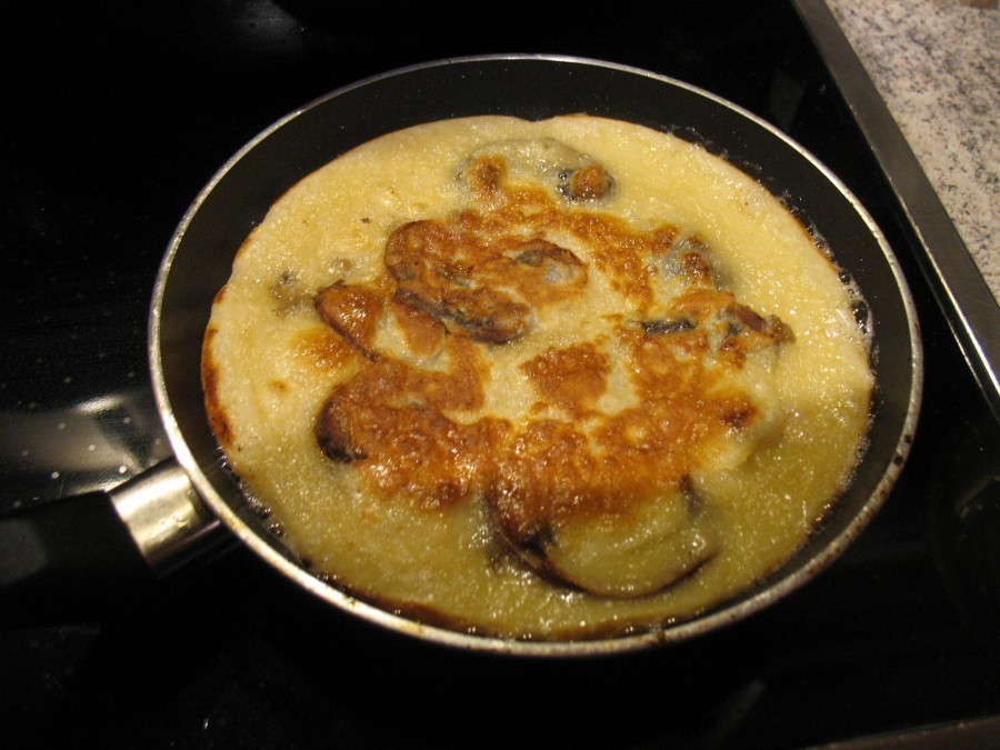 Die Champignon-Zwiebel-Knoblauch-Mischung wird mit Teig bedeckt.  Die Pfannkuchen werden von beiden Seiten goldbraun gebacken.