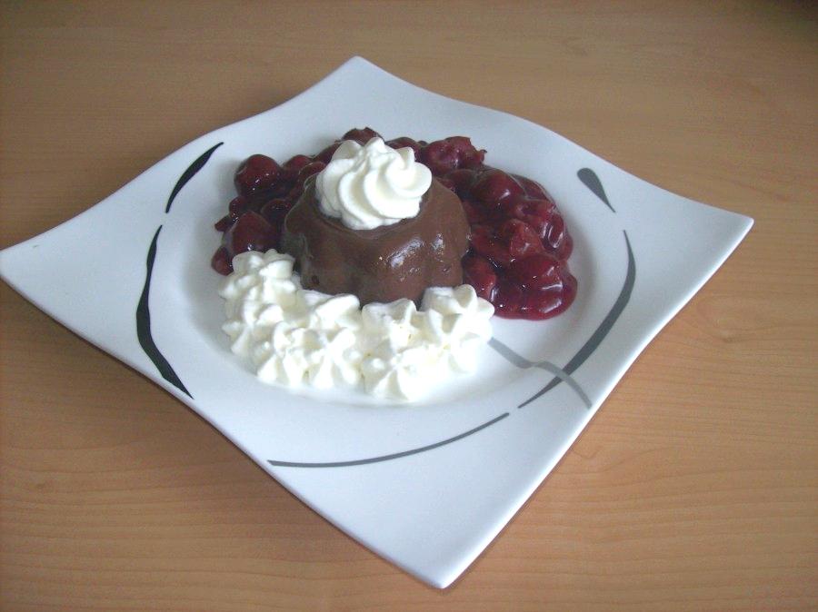 Das warme Kirschkompott wird um den Pudding drapiert und die Sahne gibt den letzten Pfiff beim Dessert.