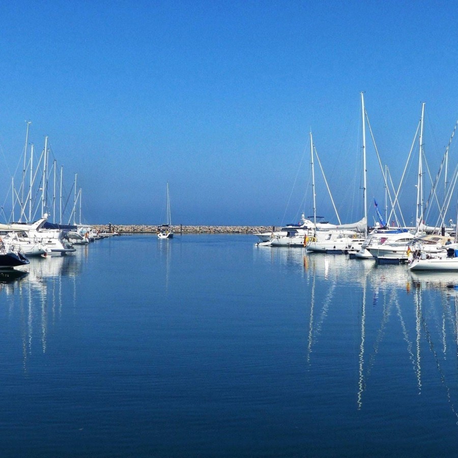 Blaues Wasser und kleine sowie große Schiffe und Boote, die sich darin spiegeln. Weißt du, welchen Hafen das Bild zeigt?