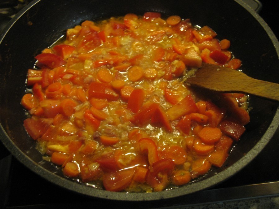 Die Tomaten- und Paprikastücke gibt man zu der Gemüse-Schinken-Mischung auf die Pfanne, löscht mit etwas Nudelwasser ab, würzt das Ganze und lässt alles etwa zehn Minuten einkochen.  