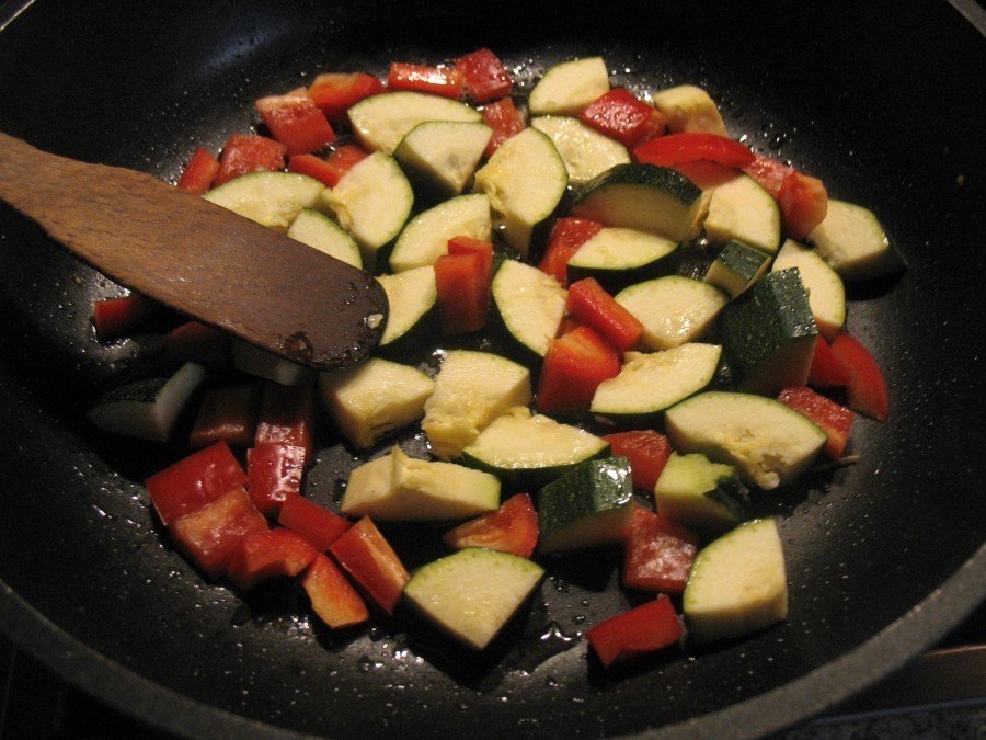 Die Hälfte der Paprika-Zucchini-Stücke werden in einer hohen beschichteten Pfanne im heißen Öl kurz angebraten.