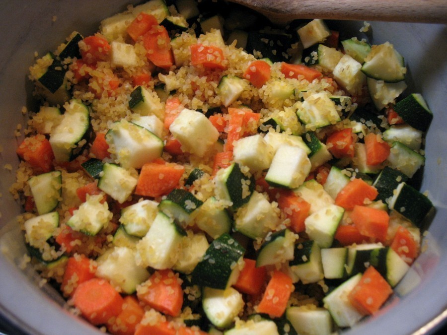 Bulgur, Karotten- und Zucchinistücke werden mit der Gemüsebrühe in einen Topf gegeben.