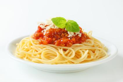 Die Spaghetti Bolognese mit frischem Parmesan und Basilikum servieren.