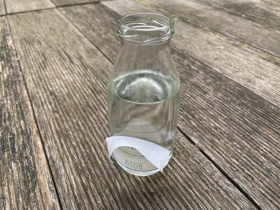 Aufgeklebte Etiketten mit heißem Wasser und Olivenöl von einem Glas entfernen.