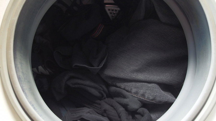 Schwarze Kleidung zusammen mit Efeublättern in der Waschmaschine waschen