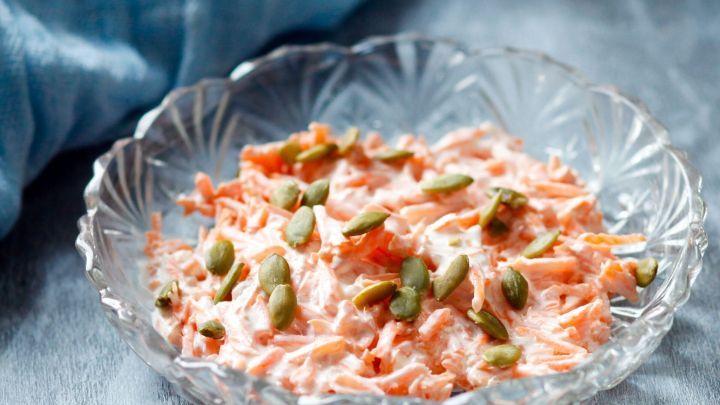 Der leckere Möhrensalat wird mit einem geriebenen Apfel und Kürbiskernen verfeinert. Die Soße besteht aus fettarmen Joghurt sowie Kürbiskernöl.