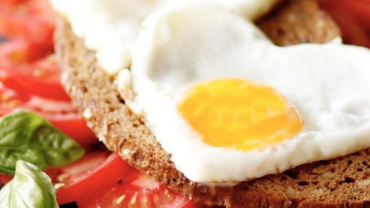 Wenn die Brotscheibe goldbraun und knusprig geröstet ist, zuerst die Tomatenscheiben und zum Schluss das Spiegelei drauflegen.