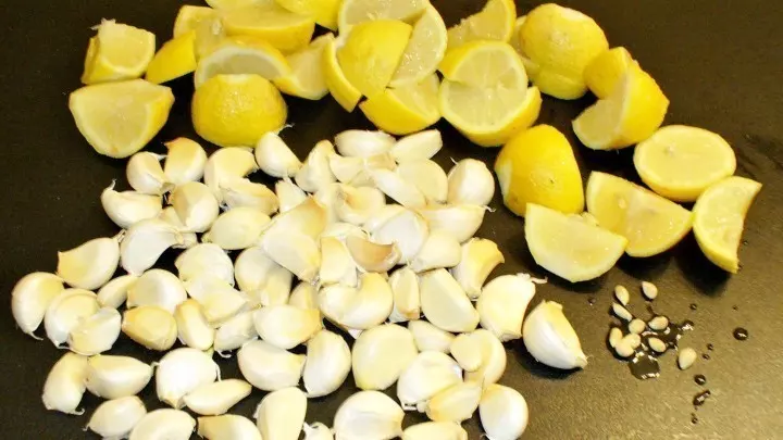 Zitronen in Stücke schneiden, Knoblauchknolle in Zehen teilen.