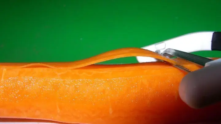 Die geschälte Möhre mit einem Sparschäler in Streifen schneiden