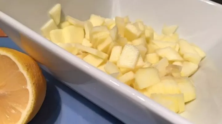 Den geschälten Apfel in Würfel schneiden und mit Zitronensaft vermischen.