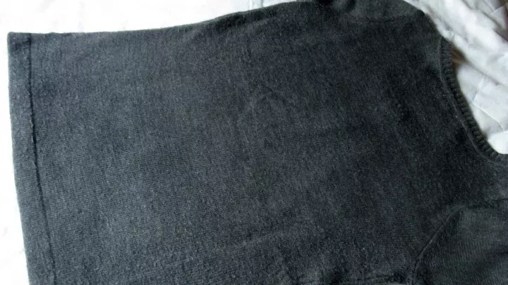 Der Pullover wird mit der Vorderseite nach unten auf eine glatte Unterlage gelegt.