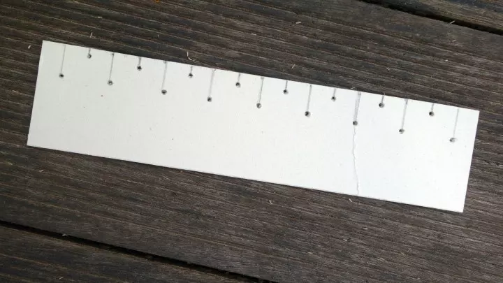 Ein fünf Zentimeter breiter Pappstreifen mit Lochmuster dient als Hilfe für das Ziermuster.