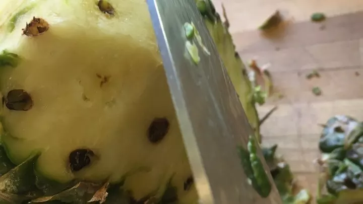 Als nächstes wird die äußere Schale der Ananas mit dem Messer komplett entfernt.