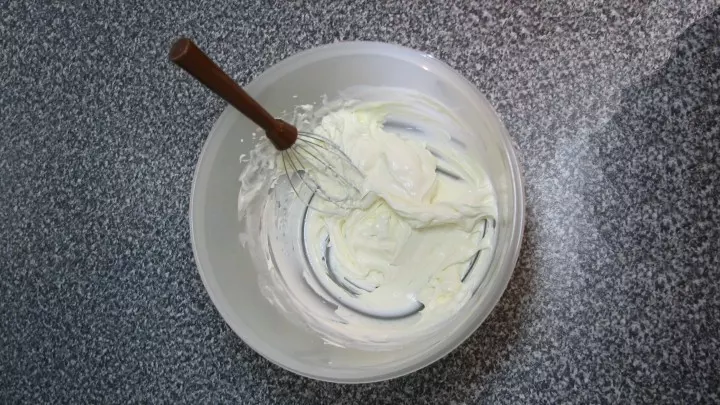 Den Frischkäse mit 1 EL Milch (Sahne oder Wasser) cremig rühren. Den ausgekühlten Kuchen zwischen den Händen fein zerreiben und mit einem Teigschaber unter den Frischkäse ziehen.
