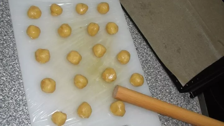 Aus der abgekühlten festen Masse werden jetzt kleine marzipankartoffelgroße Kugeln auf einem Brett gerollt.  