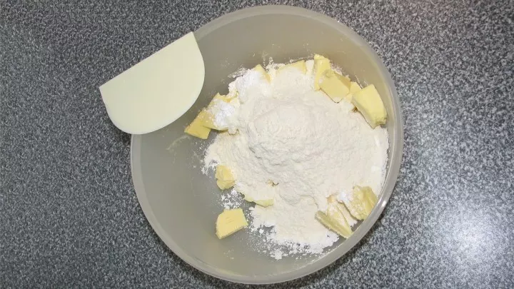 Kalte Butter in Stücke schneiden und in die Schüssel geben. Puderzucker, Mehl und Backpulver dazu und dann mit der runden Seite des Teighörnchens die Butter “sozusagen“ schneiden.