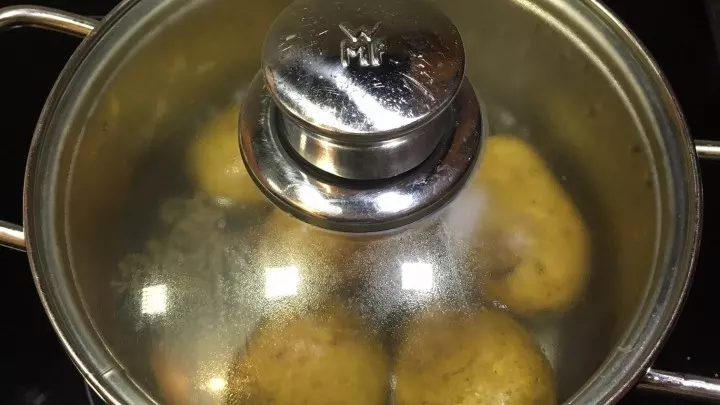 Die Kartoffeln mit Schale in Salzwasser mit dem Kümmel ca. 20 Minuten kochen, nach dem Abschrecken in sehr feine Scheiben schneiden.