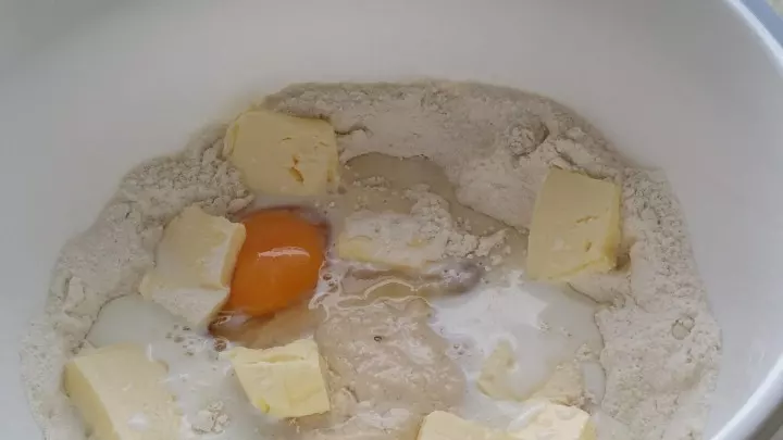 Danach werden zu der mit Milch aufgelösten Hefe, dann die Butter, das Ei und die restliche lauwarme Milch dazugeben.