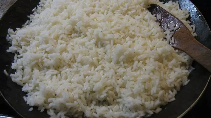In einer anderen Pfanne die Butter schmelzen, den abgetropften Reis zugeben und gut durchschwenken.