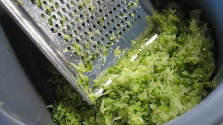 Die Zucchini werden gewaschen und fein geraspelt, dann wird mit einem Geschirrtuch die Feuchtigkeit leicht ausgedrückt.