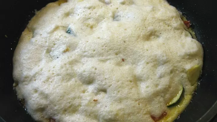Die Hälfte der Eier-Milch-Käse-Mischung wird zu dem Gemüse auf der Pfanne gegeben und bei mittlerer Hitze wird alles gebraten, bis die Eimasse stockt.