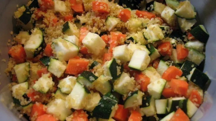 Bulgur, Karotten- und Zucchinistücke werden mit der Gemüsebrühe in einen Topf gegeben.
