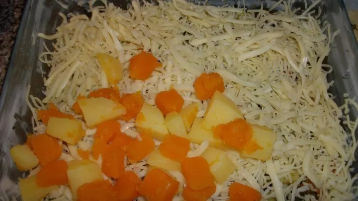 Die Hälfte von jedem der drei Käsesorten drüber schichten und eine weitere Schicht Kartoffeln und Kürbis. 