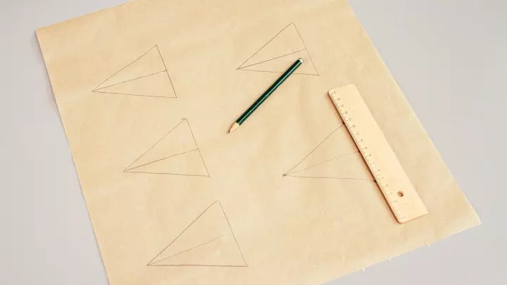 Breite das Backpapier auf einem Tisch aus und zeichne tannenbaum-große Dreiecke darauf. Das erleichtert dir später die Arbeit!